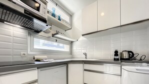 Une cuisine moderne avec des meubles blancs, un plan de travail noir et une fenêtre au-dessus de l’évier.