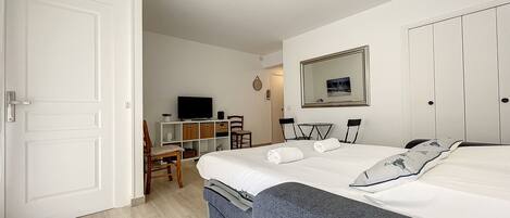 A hotel room with a bed, a desk with a TV, a chair, and a wardrobe.