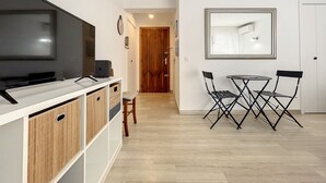 Une cuisine moderne dotée d’un téléviseur à écran plat, de meubles en bois et d’un coin repas avec une petite table et des chaises.