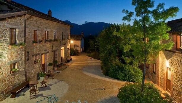 A stone building with a courtyard, benches, and potted plants. - Cottage with breathtaking views of the Sibillini Mountains (Marche)