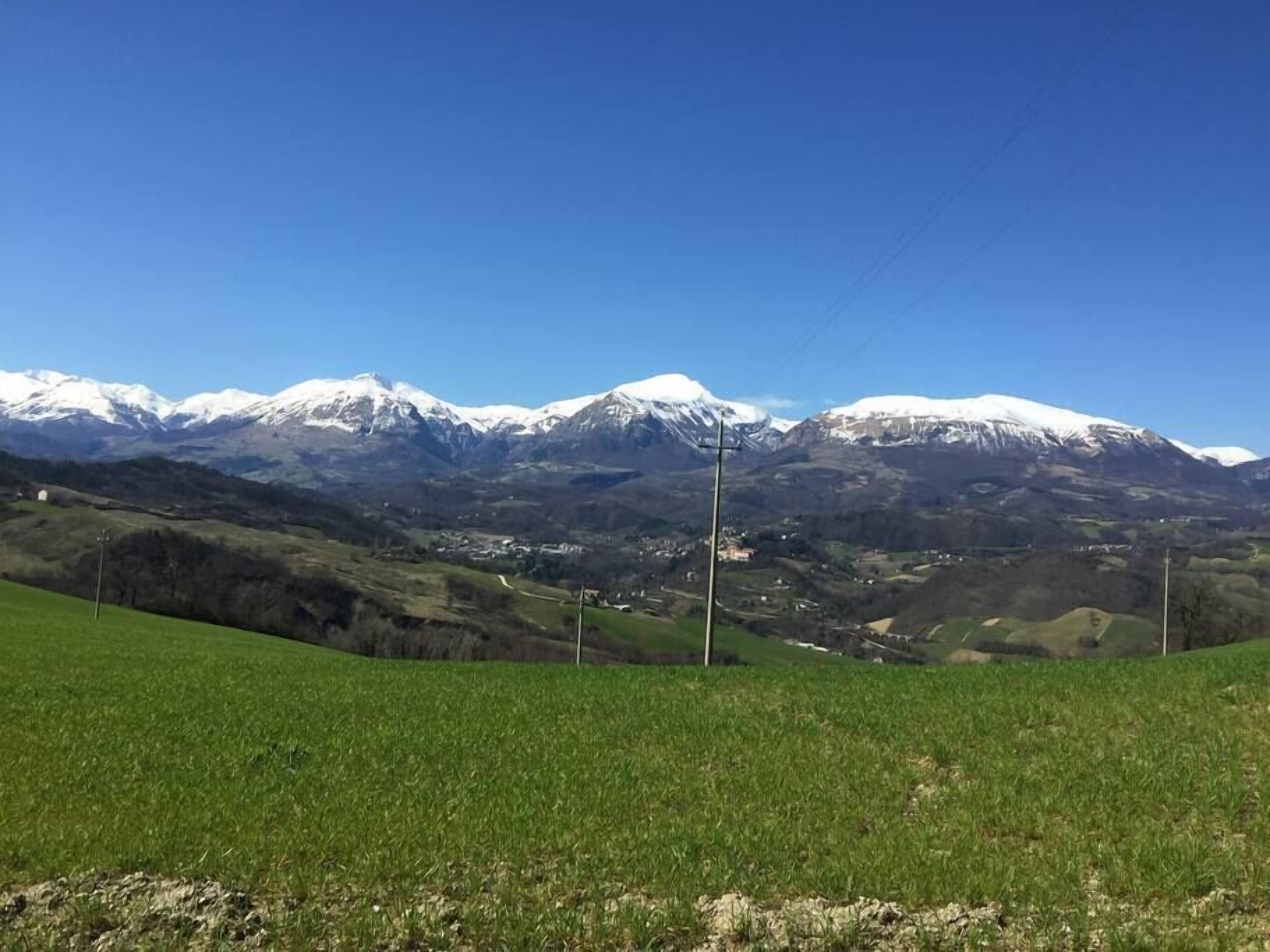 Un paysage montagneux avec des sommets enneigés et une vallée verdoyante.
