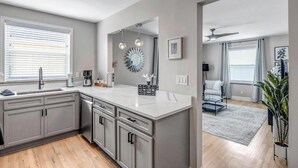 A modern kitchen with grey cabinetry, a central island, and pendant lighting.