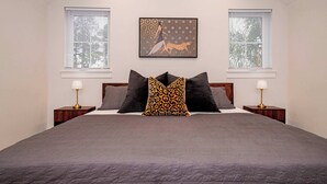 A bedroom with a large bed, two bedside tables with lamps, and a wall-mounted picture.