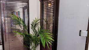 A hallway with a wooden floor, a potted plant, and two sliding doors with metal blinds.