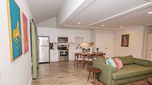 A modern kitchen with white cabinets, stainless steel appliances, and a dining area with wooden chairs and a table.