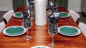 A dining table set with green plates and silverware, surrounded by chairs.