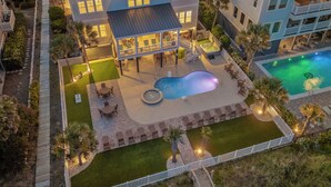 Ein zweistöckiges Haus mit Schwimmbecken, Außenbereich mit Sitzgelegenheiten und einer überdachten Terrasse.
