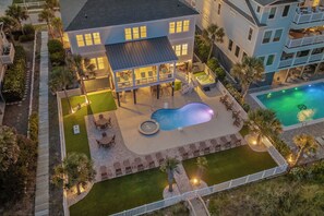 Une maison à deux étages dotée d’une piscine, d’un espace salon extérieur et d’un patio couvert.