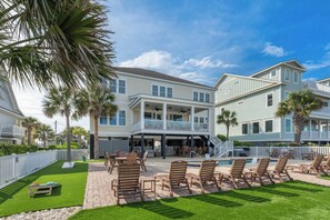 A two-story building with a pool, outdoor seating, and a white fence. - The Pressian: Oceanfront, Pool & Hot Tub (Garden City Beach)