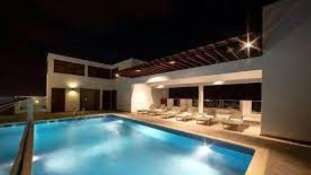 Una piscina moderna all'aperto con lettini e un'area lounge coperta di notte.
