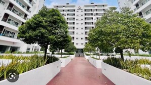 Un moderno palazzo residenziale con un cortile interno, circondato da vegetazione e un vialetto rosso.