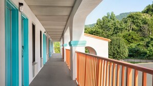 A corridor with teal doors, a concrete ceiling, and a view of a forested hillside. - 3 minutes to Cozy one Bedroom in Lookout Mountain  (Chattanooga)
