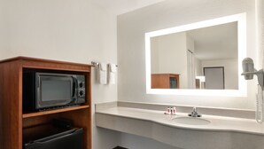 A hotel bathroom with a wooden cabinet containing a microwave, a sink with a mirror above it, and a hairdryer on the wall. - 3 minutes to Cozy one Bedroom in Lookout Mountain  (Chattanooga)