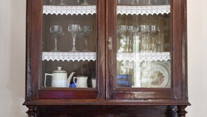 Un meuble en bois foncé doté de portes en verre, de deux tiroirs et d’un dessus décoratif.