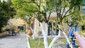Une terrasse en pierre avec des meubles d’extérieur, un espace de jeux pour enfants et un bâtiment doté de balcons.