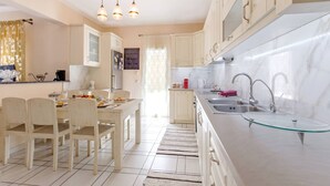 Une cuisine moderne avec des meubles blancs, un plan de travail en verre et un coin repas comprenant des chaises et une table.