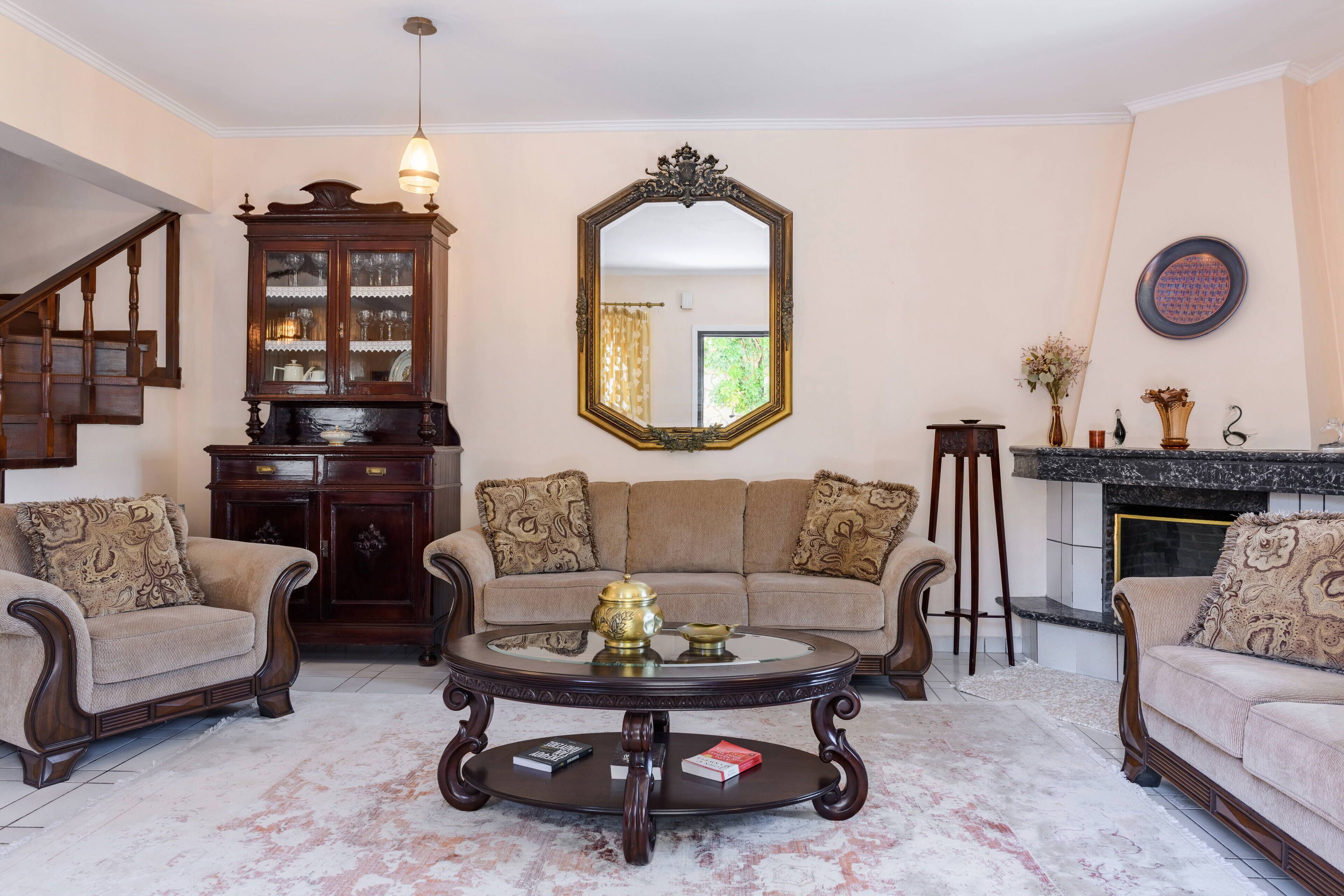 A living room with a sofa set, a coffee table, a cabinet, and a fireplace.