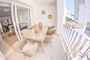 A balcony with wicker furniture, a glass table, and a view of the cityscape. - Palmas 101: 1BR w Rooftop Pool, 1 Block to Beach (Bucerías)