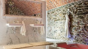 Un baño con dos lavamanos, un espejo y una pared de piedra.