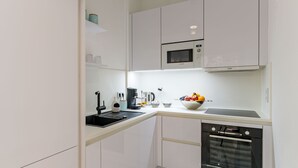 Una cocina moderna con armarios blancos, un microondas Bosch, una cafetera y un lavavajillas.
