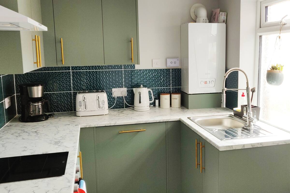 Eine kleine Küche mit Spüle, Kaffeemaschine, Toaster und Wasserkocher.