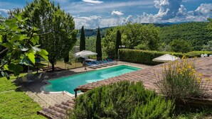 Une piscine rectangulaire à l’eau d’un bleu limpide, entourée d’une terrasse en briques et d’une pelouse.