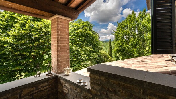 Un banc en pierre offrant une vue sur un paysage verdoyant luxuriant, situé sous une pergola en bois.