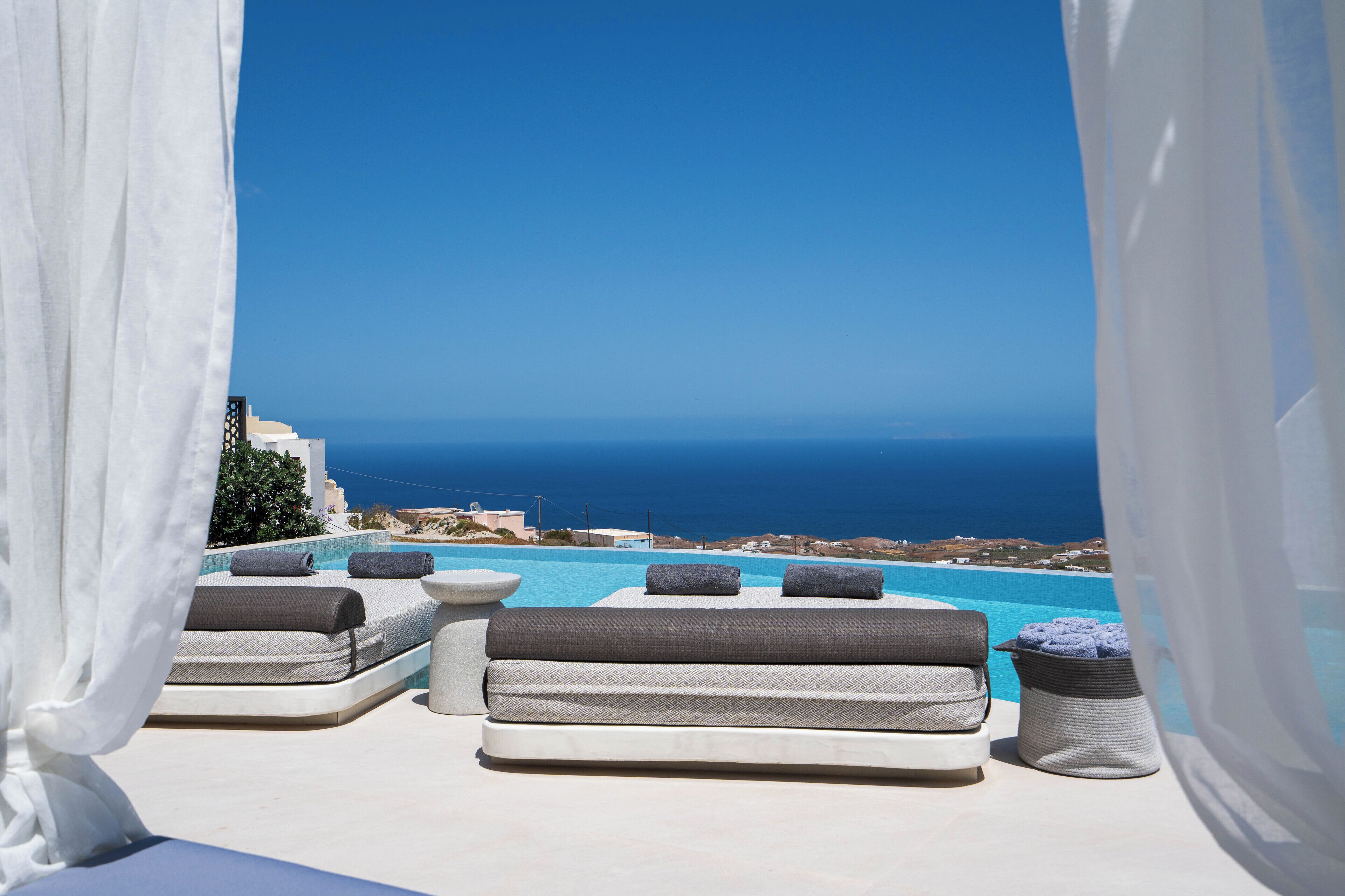 A poolside area with lounge chairs and a view of the sea.