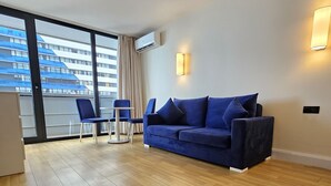 A modern living room with a blue sofa, two armchairs, and a wooden floor. - iRent Batumi Apartments (Batumi)
