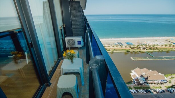 A balcony with a view of the beach and a parking area. - iRent Batumi Apartments (Batumi)