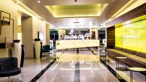 A modern hotel lobby with a reception desk, seating area, and a large digital display. - iRent Batumi Apartments (Batumi)
