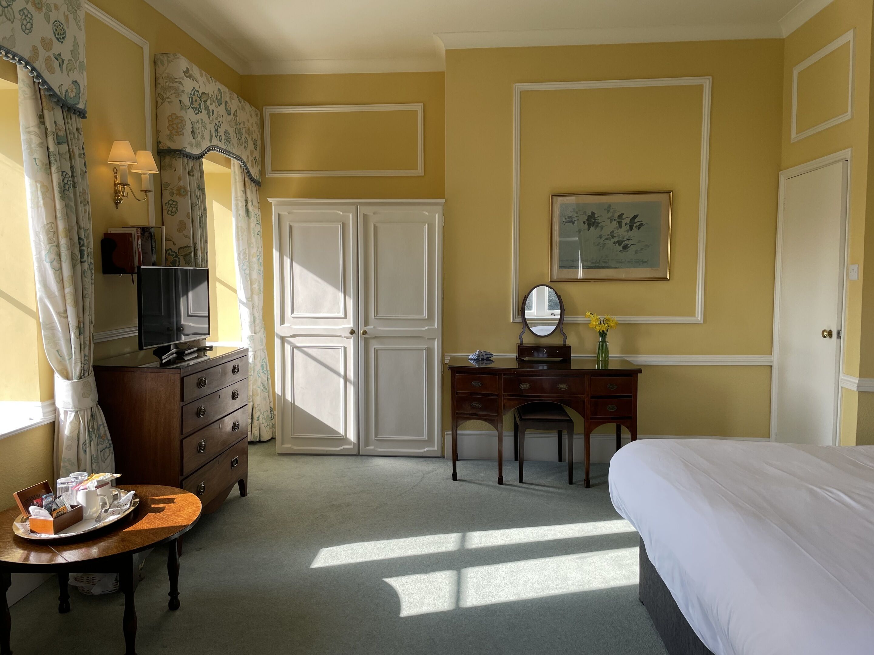 Ein Hotelzimmer mit einem Bett, einem Schreibtisch mit Spiegel, einem Schminktisch und einem Fernseher.
