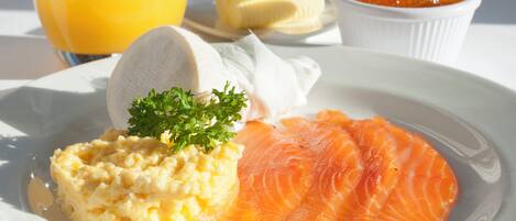 A plate with salmon, scrambled eggs, and a glass of orange juice.