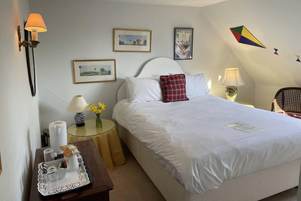 A neatly arranged hotel room with a bed, bedside tables, a small table with a tray, and wall-mounted lamps.