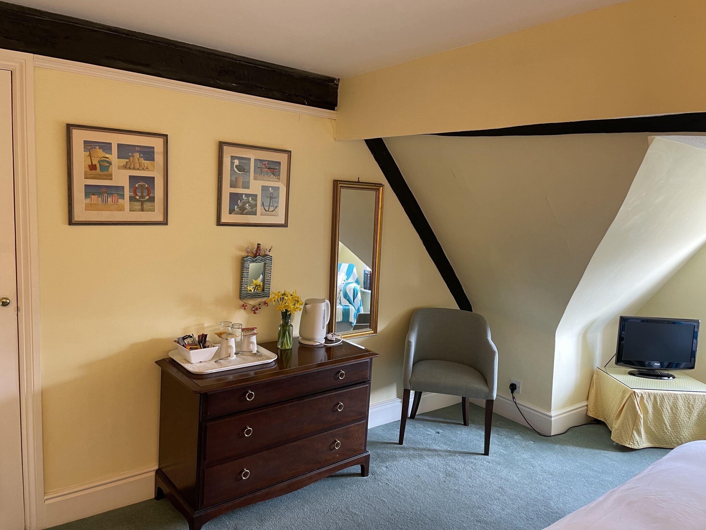 A bedroom with a dresser, chair, and a television on a small table.