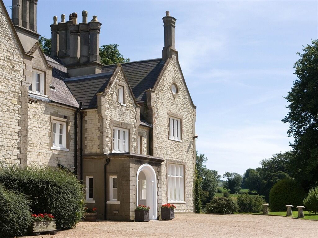 A stone building with a large arched entrance, multiple chimneys, and a gravel driveway.