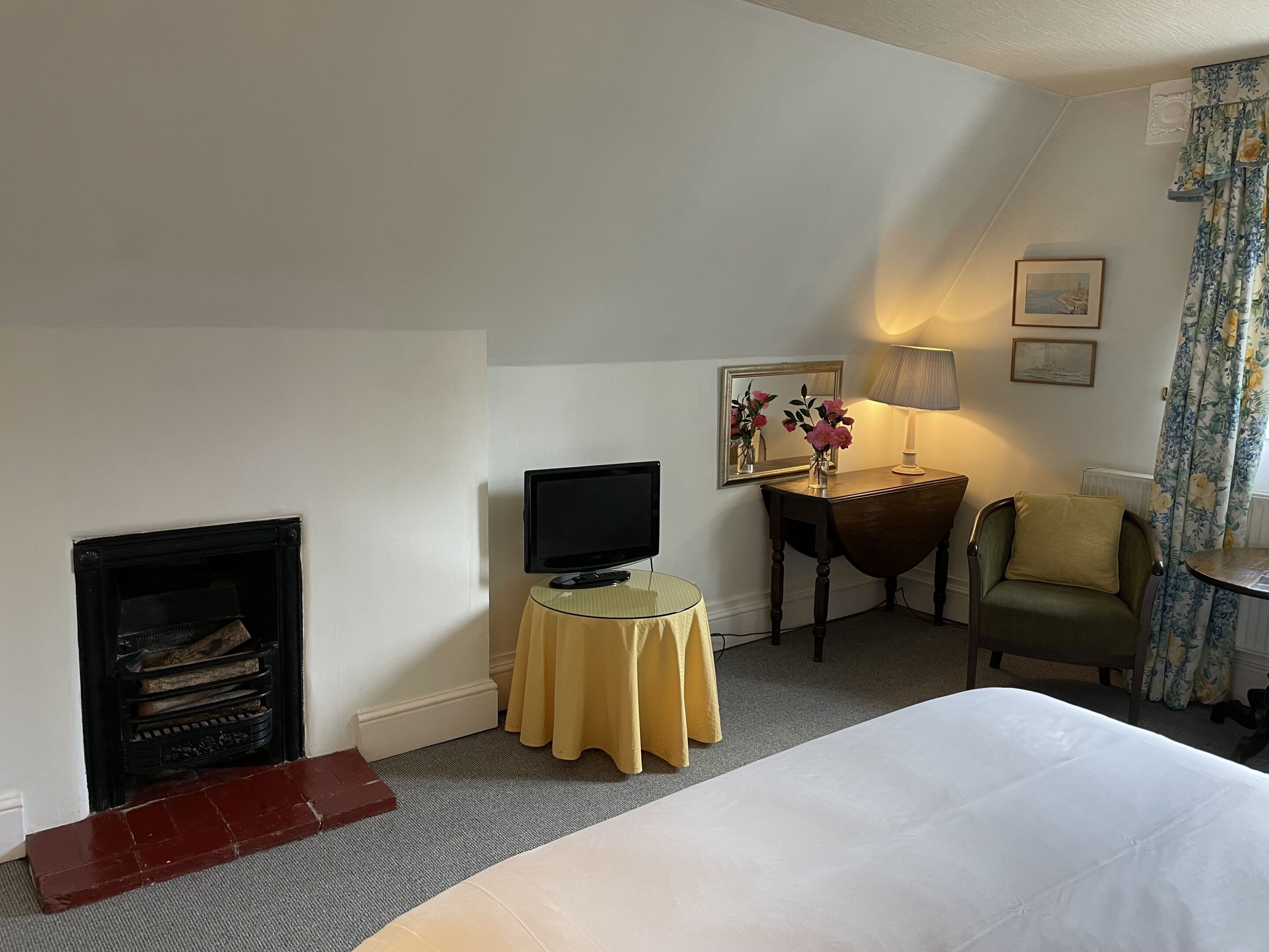 Une chambre d’hôtel avec un lit, un téléviseur posé sur une petite table, une cheminée, une lampe et un fauteuil.