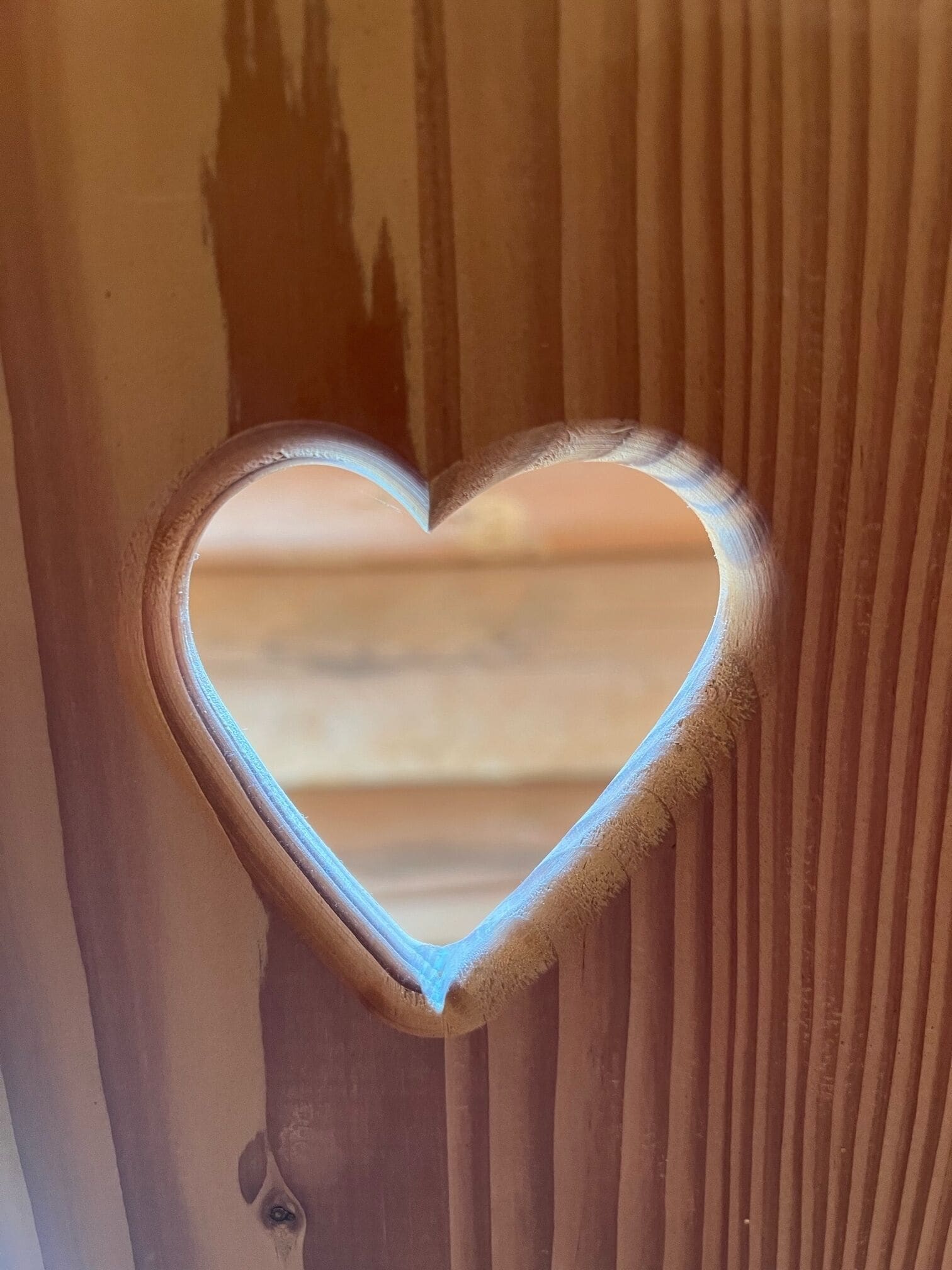 A heart-shaped mirror with a wooden frame.