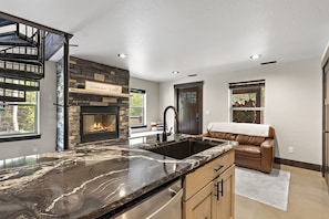 A modern kitchen with a stone fireplace, a large sink, and a built-in oven.