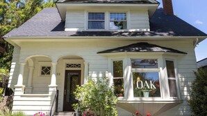 A two-story white house with a dark roof, a front porch, and a window with the name "OAK" on it. - Historic Flat in Downtown Boise (Boise)