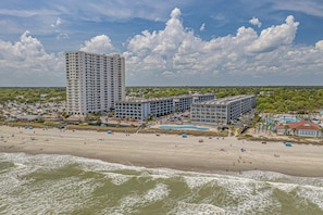 A beachfront hotel with multiple buildings, a pool area, and a beach.