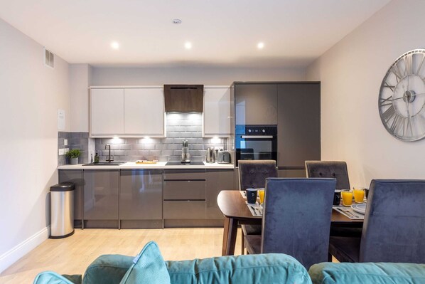 Enjoy a compact kitchen with stainless steel appliances, oven, and microwave, plus a dining area with a table and chairs.