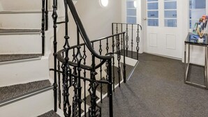 Una escalera con barandales negros ornamentados que conduce a un rellano.