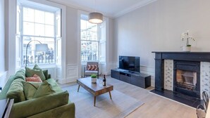 Una sala de estar con un sofá verde, una mesa de centro, un televisor y una chimenea.