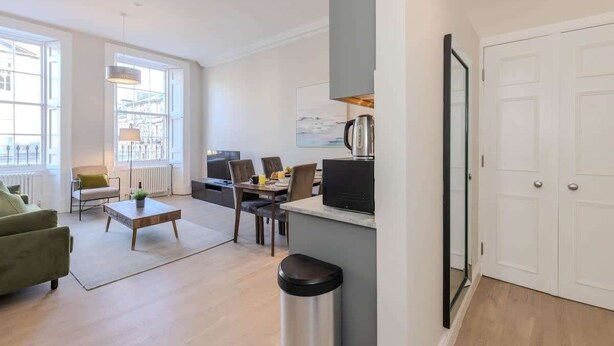 A modern living room with a sofa, coffee table, and dining area. - Edinburgh City Centre 2 Bed Apartment (Edinburgh)