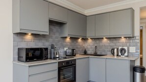Een moderne keuken met grijze kastjes, een magnetron, broodrooster, waterkoker en oven.