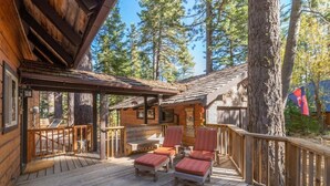 A wooden cabin with a deck, outdoor seating, and a large tree nearby. - Rustic Beauty in Chamberlands Full Beach & Pool (Homewood)