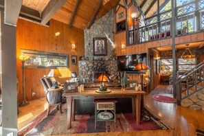 A rustic interior with a stone fireplace, wooden beams, and a large TV mounted on the wall.