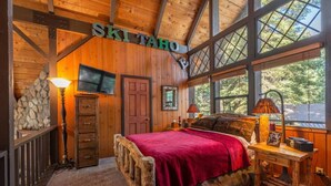 A cozy room with a bed, a TV, and a stone wall. - Rustic Beauty in Chamberlands Full Beach & Pool (Homewood)