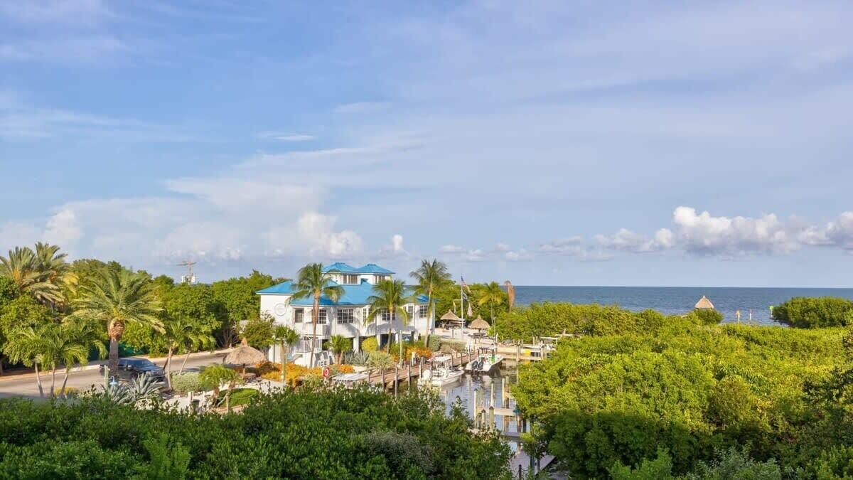A coastal property with a large building, a dock, and a view of the sea.